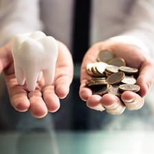 a person holding money in one hand and a model of a tooth in the other